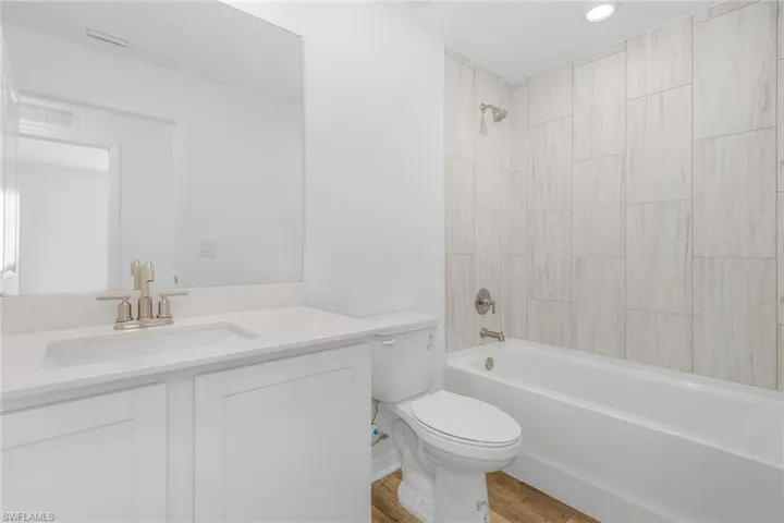 Full bathroom with hardwood / wood-style flooring, toilet, vanity, and tiled shower / bath