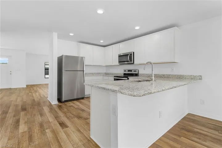 Kitchen featuring sink, white cabinets, light hardwood / wood-style flooring, and appliances with stainless steel finishes