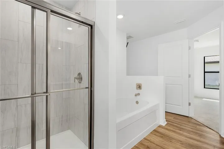Bathroom with independent shower and bath and hardwood / wood-style floors