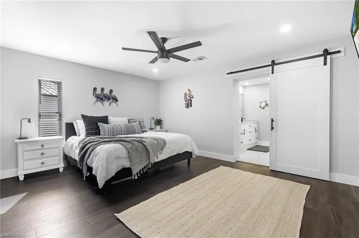Bedroom with recessed lighting, visible vents, a barn door, and dark wood-type flooring