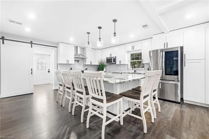 Dining room with recessed lighting, dark wood-style flooring, a barn door, and visible vents