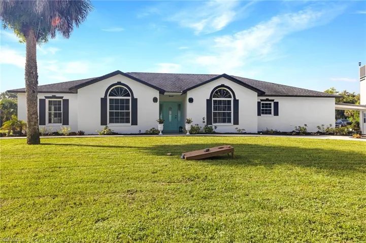 Ranch-style home featuring roof with shingles, a front yard, and stucco siding