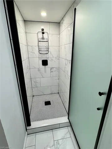 Full bathroom featuring baseboards, a stall shower, and marble finish floor