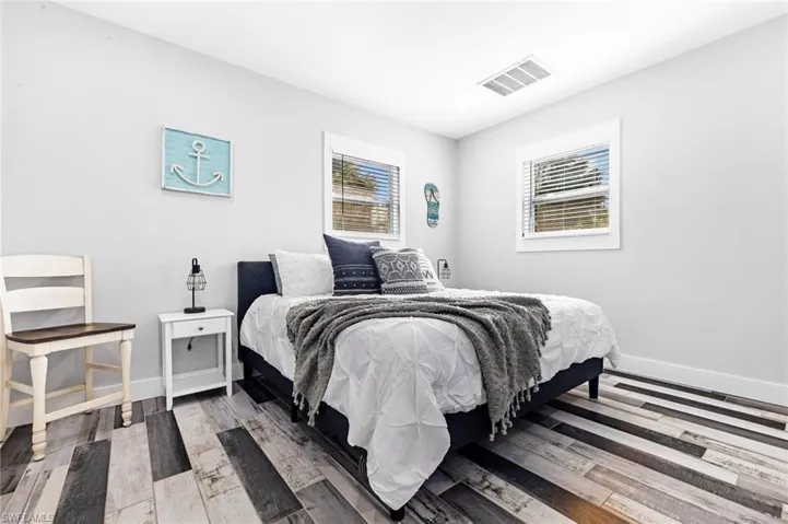 Bedroom with baseboards, visible vents, and wood finished floors