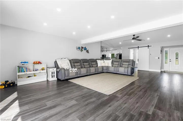 Living room featuring recessed lighting, a barn door, and dark wood-style flooring