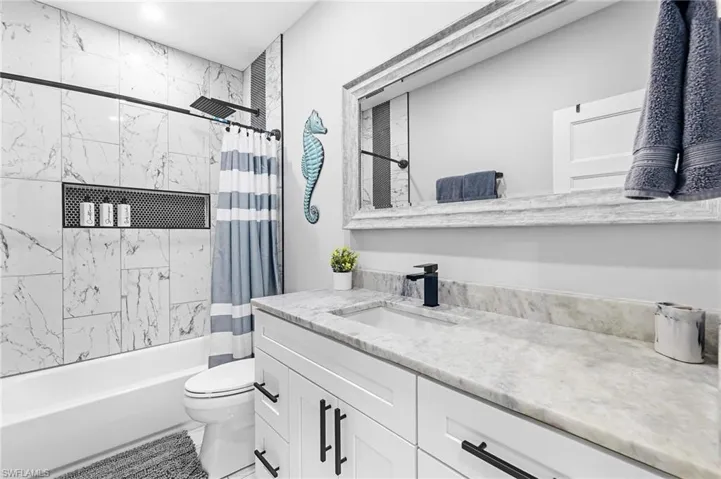 Full bathroom featuring vanity, shower / bathtub combination with curtain, and toilet