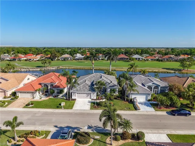 Residential property featuring a paver driveway, an attached garage, a tile roof, and a meticulously landscaped yard