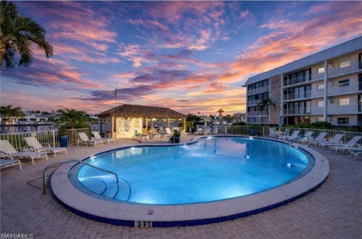 Pool at dusk featuring a patio and a community pool