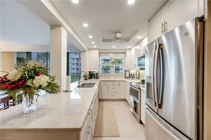 Kitchen with stainless steel appliances, light stone counters, recessed lighting, a peninsula, and white cabinetry