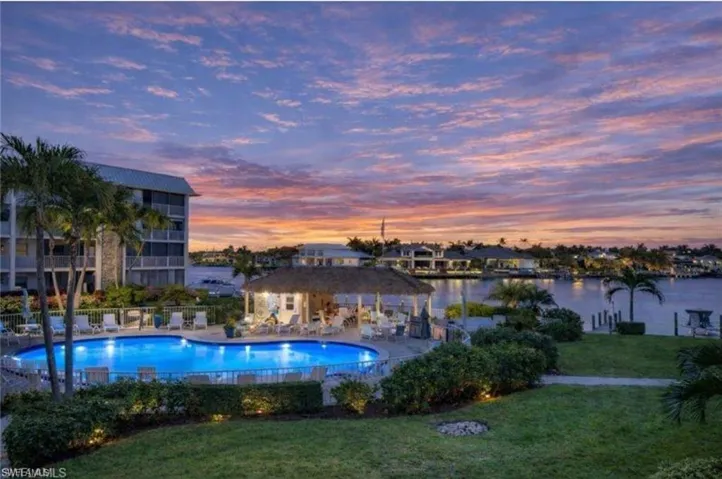 Pool at dusk featuring a patio and a community pool
