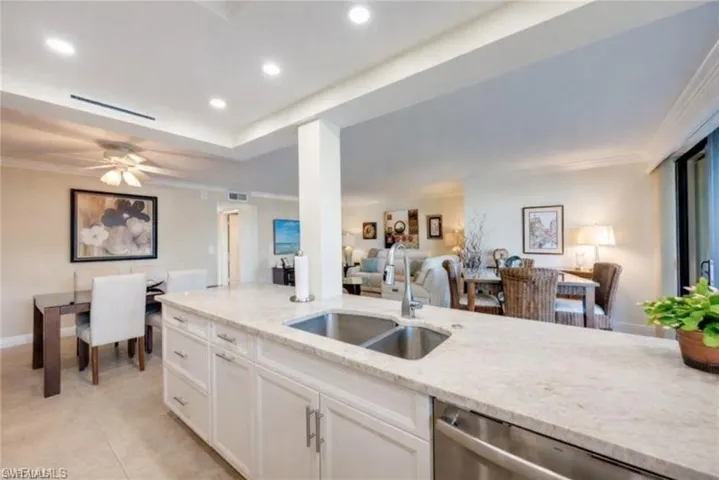 Kitchen featuring crown molding, dishwasher, light stone counters, white cabinetry, and open floor plan