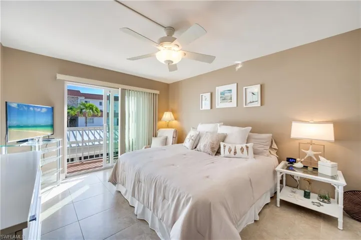 Bedroom with access to exterior, light tile patterned floors, and a ceiling fan