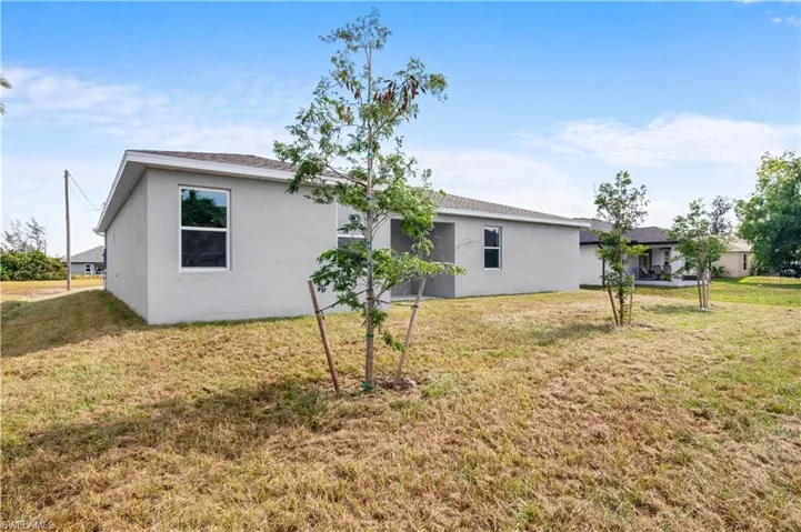 View of side of home with a lawn and stucco siding