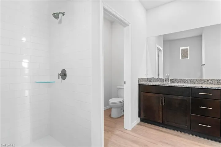 Bathroom featuring vanity, light wood-style floors, and a shower stall
