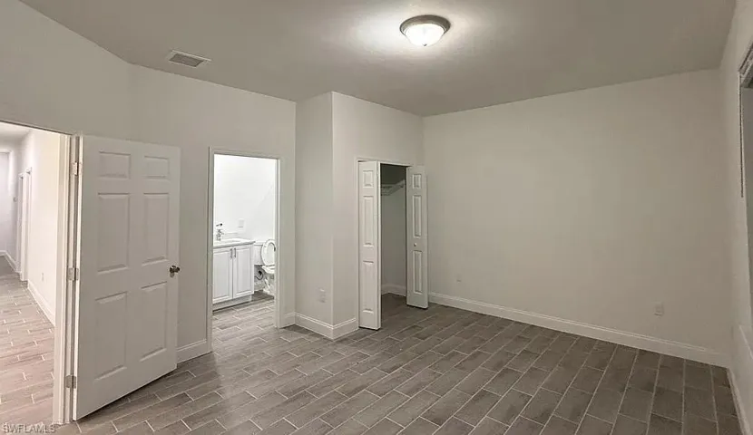 Unfurnished bedroom with a closet, wood tiled floors, and connected bathroom