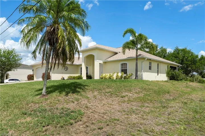 Ranch-style home with an attached garage, a front yard, and stucco siding