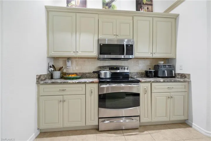Kitchen with cream cabinetry, stainless steel appliances, and decorative backsplash
