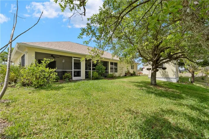 Rear view of property with stucco siding, a yard, a sunroom, roof with shingles, and a ceiling fan