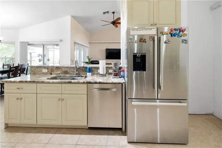Kitchen with cream cabinetry, stainless steel appliances, a ceiling fan, light stone counters, and open floor plan