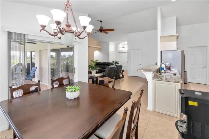 Dining room featuring ceiling fan, hanging lights, lofted ceiling, and light tile patterned flooring