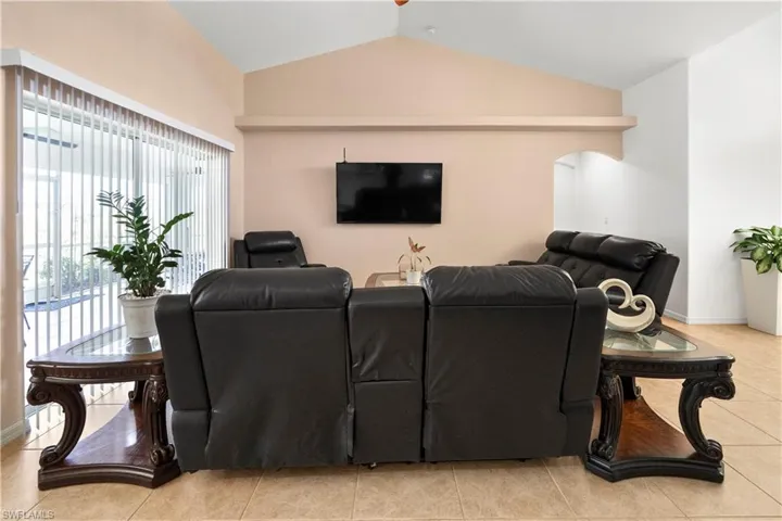 Living area featuring light tile patterned flooring, arched walkways, and a ceiling fan