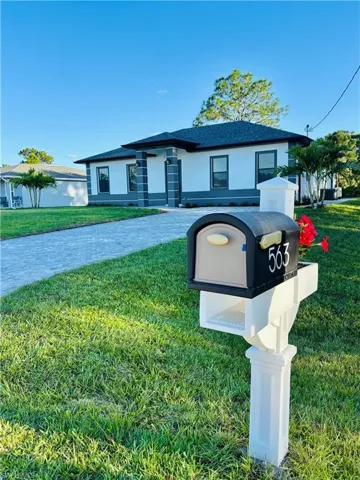 View of front of house featuring a front lawn, stucco siding, decorative driveway, and roof with shingles