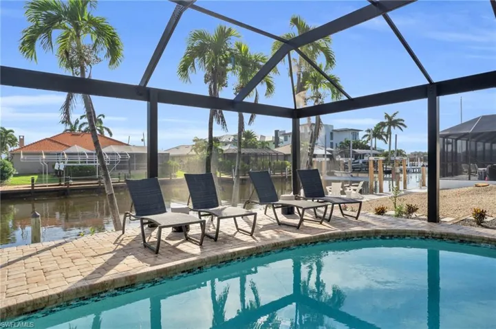 Relax around the spacious pool area and enjoy the view of the gulf access canal and blue skies - Digitally Enhanced