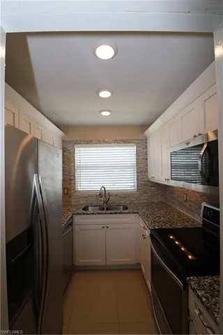 Kitchen featuring fridge, dishwasher, range, a sink, and backsplash