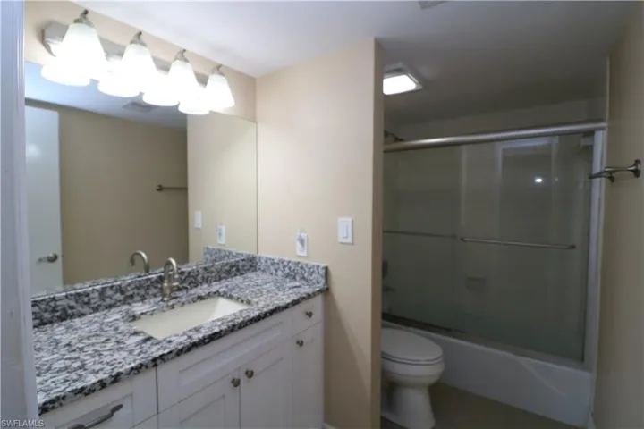 Full bathroom with toilet, vanity, and combined bath / shower with glass door