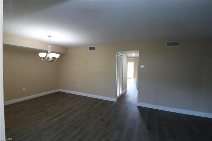 Unfurnished room featuring visible vents, baseboards, and dark wood-type flooring
