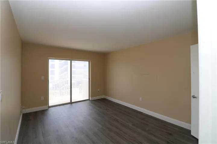 Unfurnished room with baseboards and dark wood-style flooring