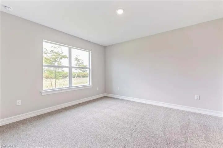 Carpeted spare room featuring baseboards