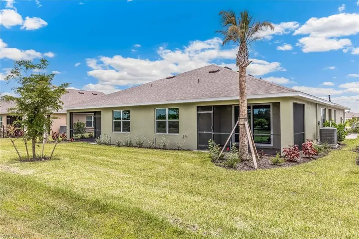 Back of house featuring stucco siding, a shingled roof, and a lawn