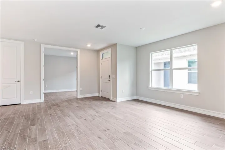 Empty room with light wood-style floors and recessed lighting