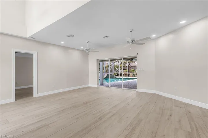 Family room featuring light wood finished floors, recessed lighting, a ceiling fan, and a high ceiling