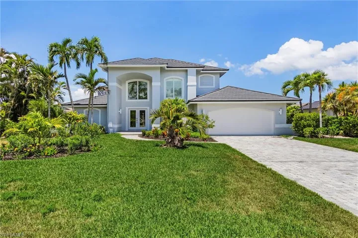 View of front of home with french doors, stucco siding, a front yard, decorative driveway, and an attached garage
