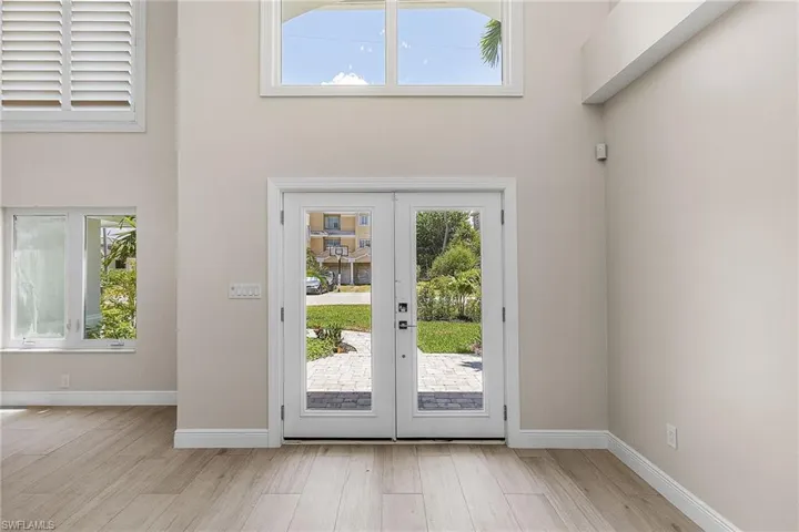 Doorway to outside with french doors, wood finished floors, and a high ceiling