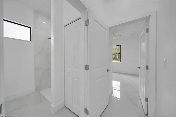 Bathroom featuring a closet, a marble finish shower, and light marble finish flooring