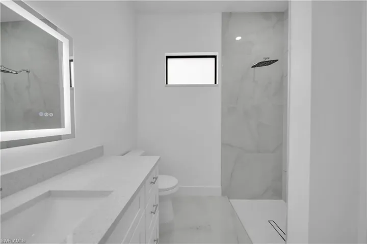 Full bathroom featuring vanity, a marble finish shower, and light marble finish floors