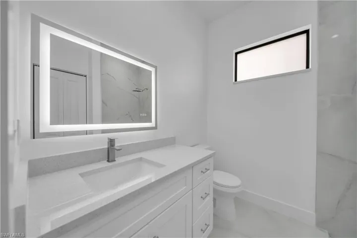 Bathroom featuring vanity and a marble finish shower