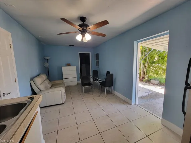 Living room with light tile patterned floors, ceiling fan, and baseboards