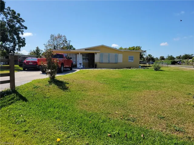 View of front of house with concrete driveway and a front lawn