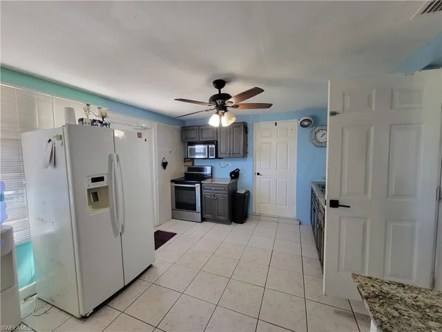 Kitchen with visible vents, appliances with stainless steel finishes, light tile patterned flooring, and a ceiling fan