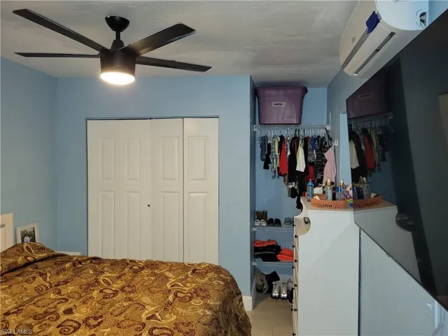 Bedroom featuring a ceiling fan, tile patterned floors, a closet, and an AC wall unit