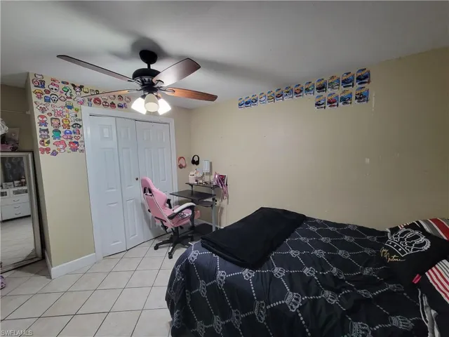 Bedroom featuring a closet, light tile patterned flooring, ceiling fan, and baseboards