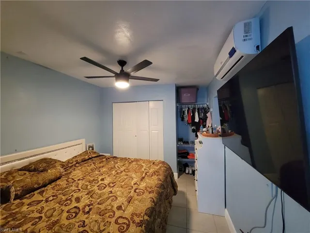 Bedroom featuring a wall mounted AC, light tile patterned floors, a closet, and ceiling fan