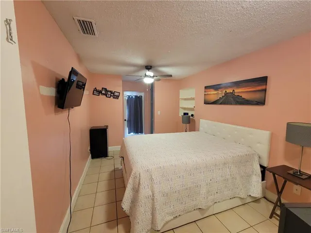 Bedroom with visible vents, a textured ceiling, a ceiling fan, and light tile patterned flooring