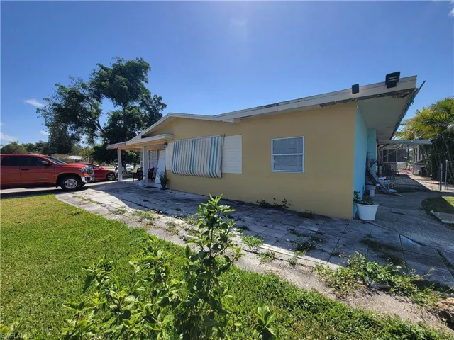 View of side of home with a patio area, stucco siding, and a lawn