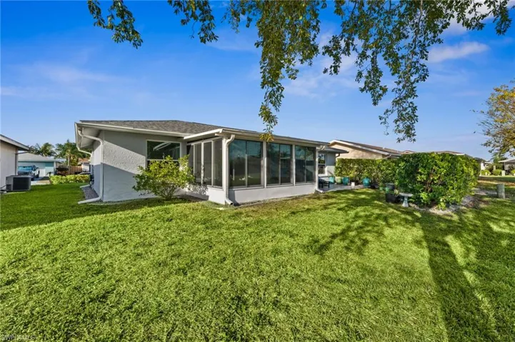 Back of house with a yard, a sunroom, and stucco siding
