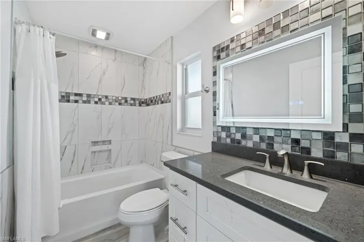 A 2nd Full bathroom with vanity, shower / tub combo, multiple shower heads and tasteful backsplash